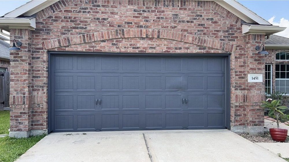 A brick house garage door repainted in dark gray